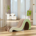 Load image into Gallery viewer, The Mint Mint - Modern Cat Scratcher & Stretching Board, featuring a sleek and contemporary design crafted from premium cardboard, rests on a hardwood floor in a sunlit room with a white armchair and an easel displaying a painting in the background.

