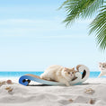 Load image into Gallery viewer, Two cats are on a sandy beach; one is lounging on the Nelo Nelo - Surf Wave Cat Furniture & Cardboard Scratcher by Nelo Nelo, made from recycled cardboard, while the other looks on. Seashells and palm leaves are visible, with the ocean and blue sky in the background. The scratcher helps maintain healthy claws while being eco-friendly.

